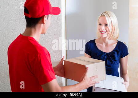 Junge Frau, die die Boxen von Delivery Man Stockfoto