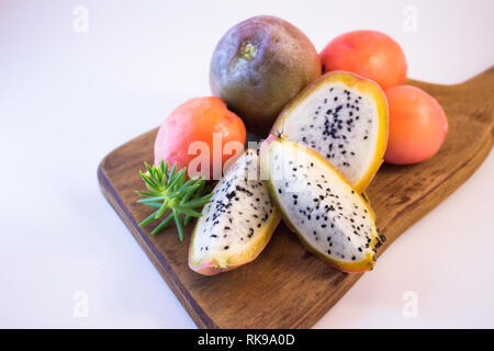 Exotische Früchte von Kaktus auf einem Holzbrett. Süß und weich Thunfisch auf weißem Hintergrund. Weiß Obst mit zahlreichen schwarzen Samen und sehr süßen Geschmack. Stockfoto