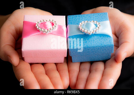 Hände halten Handwerk Geschenk blau und rosa Felder Stockfoto