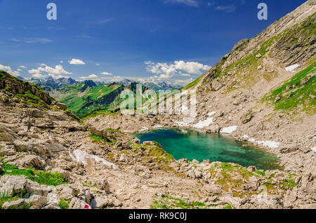 Ein kleiner See mit Schmelzwasser neben einem Wanderweg in den Alpen. Stockfoto