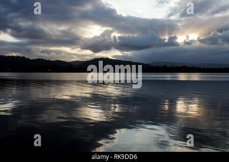 Die untergehende Sonne durch die dicke Wolkendecke scheint über Tierra Oscura - von San Cristobal Insel gesehen, Archipel Bocas del Toro, Panama Stockfoto