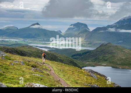 Die Frau auf dem Pfad bis zu Berg Justadtind, suchen Zurück zu Tal in Richtung Holandsmelen und Utakleiv (Mitte rechts), Austvagöy, Lofoten, Norwegen Stockfoto