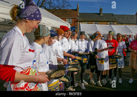 Lächelnde Damen oben Futter in den Marktplatz für den Beginn der berühmten olney Pancake Race, sagte, das älteste der Welt, Buckinghamshire, Großbritannien Stockfoto