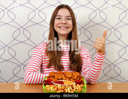 Happy Teenager mit leckeren Chicken Nuggets und Daumen hoch Stockfoto