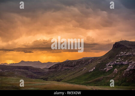 Klippen und Berge unter dramatischen bunte Sturm Wolken bei Sonnenuntergang über die Drakensberge rund um das Amphitheater, von Golden Gate gesehen Stockfoto