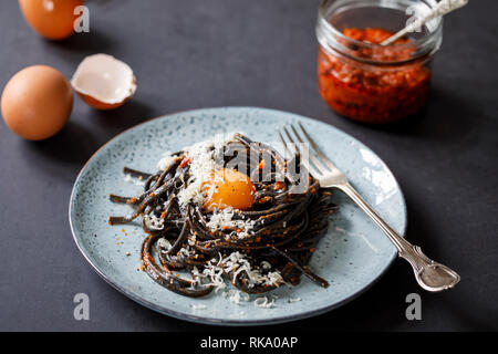 Schwarze Nudeln mit rotem Pesto und Eigelb Stockfoto