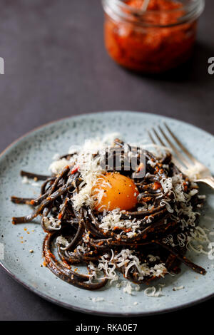 Schwarze Nudeln mit rotem Pesto und Eigelb Stockfoto