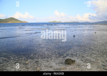 Ebbe bei Sonnenuntergang am Strand des Hl. Thomas Island, USA VI. Wellen aus dem Meer und die fernen Inseln am Horizont. Stockfoto