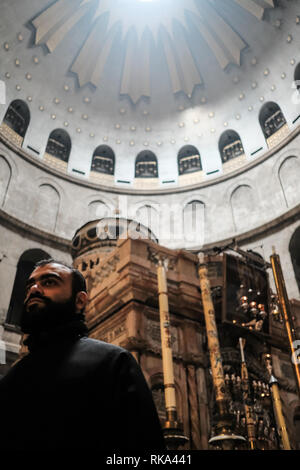 Jerusalem, Israel. 10. Februar, 2019. Ein Priester an der Edicule des Grabes in der Kirche des Heiligen Grabes. Die 'Gefängnis von Christus", eine kleine griechisch-orthodoxe Kapelle in der Kirche des Heiligen Grabes, wo Jesus die traditionell von römischen Soldaten inhaftiert war vor seiner Kreuzigung, basierend auf einer 9. Jahrhundert byzantinischen Mönch, der die Website als "der Wachstube, wo Christus mit Barabbas" inhaftiert wurde verwiesen wird, wurde vor kurzem nach Reparaturen über einen Zeitraum von mehreren Jahren durch einen Brand verursachen, der zu schweren Schäden verursacht wieder eröffnet. Credit: Nir Alon/Alamy leben Nachrichten Stockfoto