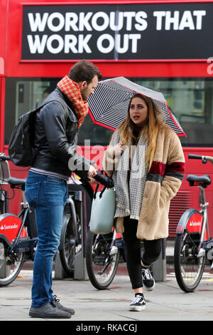 Westminster. London, Großbritannien. 10. Feb 2019. Eine Frau, die Schutz vor dem Regen unter einem Dach bei Regen in London Quelle: Dinendra Haria/Alamy leben Nachrichten Stockfoto