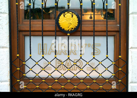 Venedig, Italien - 28 Dezember 2009: Die hölzerne Tür mit Glas zum weltberühmten Harry's Bar in Venedig, Italien, mit Logo und schöne Bügeleisen decorat Stockfoto