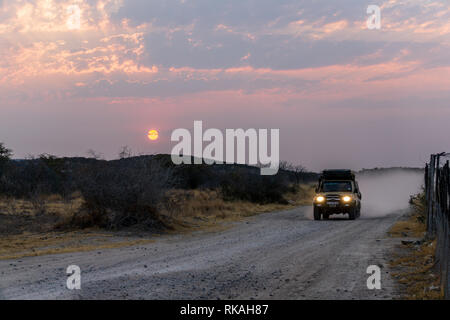 Etosha-pfanne, NAMIBIA - August 29, 2018: Fahren Offroad- und Staubwolken an Afrikanischen Schotterstraße, ein 4x4-Anschluss in Orange Lila Landschaft der Wüste, Namibia, Stockfoto