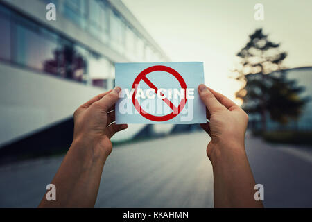 Hände halten ein Blatt Papier mit roten Einschränkung Zeichen und Wort Impfstoff. Verweigern Impfung aufgrund der möglichen gesundheitlichen Problemen. Sagen Sie Nein zu gefälschten immunizatio Stockfoto