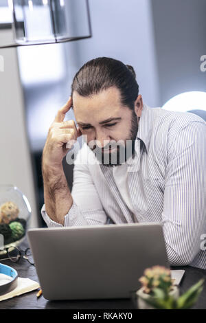 Dunkelhaarige bärtiger Mann im gestreiften Hemd suchen ernsthafte Stockfoto