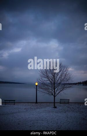 Eine Laterne leuchtet in einem Lakeside Park in Skaneateles, New York, USA, einer kleinen Stadt in der Finger Lake Region bei Dämmerung im Winter. Stockfoto