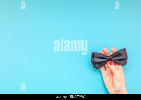 Kreative flatlay Draufsicht Retro schwarz Bow Tie frau Hände türkis Papier Hintergrund Kopie Raum. Männer Gesundheit Bewußtsein Monat Vatertag Männlichkeit co Stockfoto