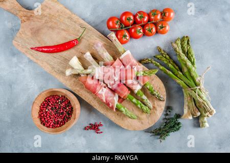 Frische organische Spargel in Schinken auf einem Schneidebrett gewickelt. Stockfoto