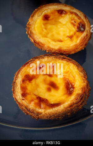 Zwei portugiesische Ei Torten Pastel de Nata. Blaue Platte Stockfoto