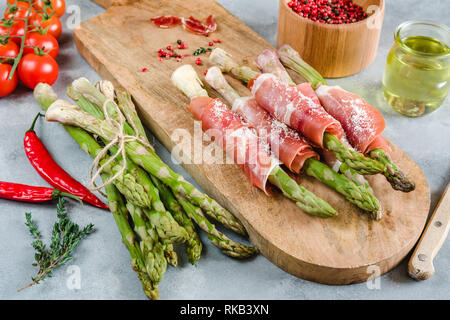 Frische organische Spargel in Schinken auf einem Schneidebrett gewickelt. Stockfoto