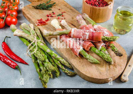 Frische organische Spargel in Schinken auf einem Schneidebrett gewickelt. Stockfoto