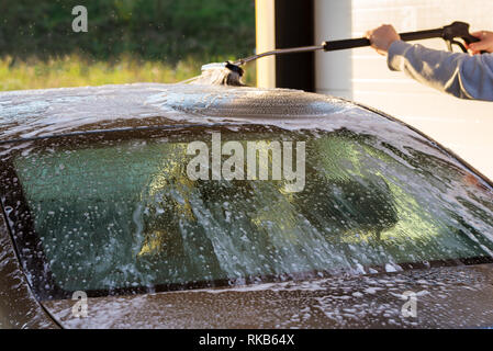 Ein Mann, sein Auto waschen unter hohem Druck Wasser. Stockfoto