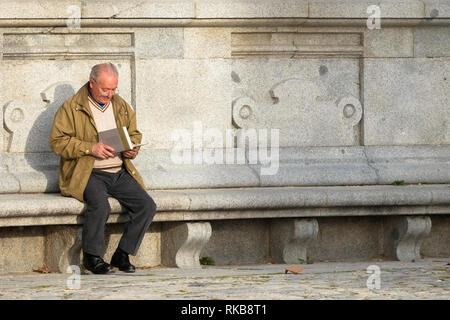 Mann auf der Bank ein Buch lesen Stockfoto