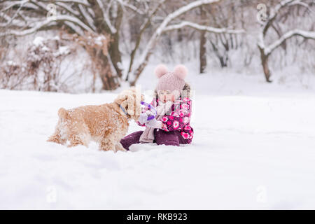 Schnee Schlacht zwischen Kleinkind und Hund im Winter Stockfoto