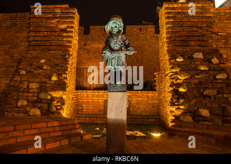 Kleine Statue von Aufständischen gegen die alte Stadtmauer in der Nacht in Warschau, Polen. Denkmal für die Kindersoldaten, die kämpften und starben während des Warschauer Uprisin Stockfoto