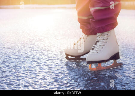 Nahaufnahme der Jungen 4 Jahre altes Mädchen tragen weiße Abbildung Schlittschuhe, Schlittschuhlaufen auf zugefrorenen See in der Natur im Freien auf kalten sonnigen Wintertag. Hobby Konzept. Stockfoto