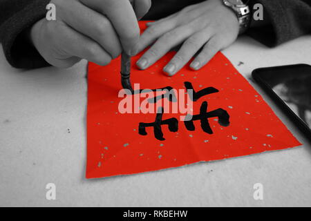 Chinesische Kalligraphie mit schwarzer Farbe und Dicke Pinsel auf roten Reis papier. Worte der Weisheit in großen Drucken angezeigt. Stockfoto