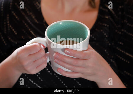 Weibliche Hände halten Kaffee am Morgen - Hintergrund - geringe Tiefenschärfe Stockfoto