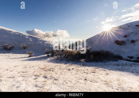 Subasio Berg (Umbrien, Italien) im Winter von Schnee bedeckt, mit Pflanzen und Sun Stockfoto