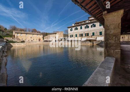 Wunderschöne Aussicht auf das mittelalterliche Dorf Bagno Vignoni mit seinem Thermalbad und ein Himmel mit Flugzeugen Trails, Toskana, Italien überschritten Stockfoto