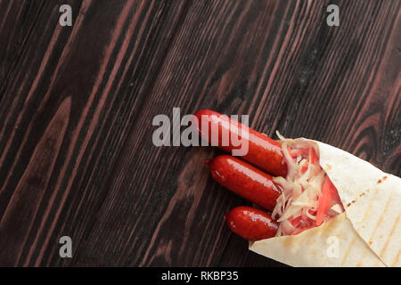 Würzige Wurst in pita Brot auf hölzernen Hintergrund. Foto mit Co Stockfoto