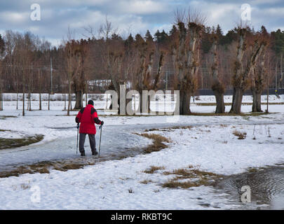 Frau gehen über Schnee und Eis mit Nordic Walking Stöcken, Upplands Vasby, Stockholm, Schweden, Skandinavien Stockfoto