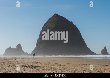 Touristen und Einheimische genießen den Strand mit Haystack Rock im Hintergrund bei Cannon Beach, Oregon, USA. Stockfoto