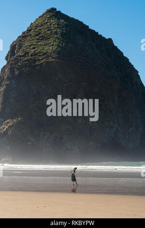 Touristen und Einheimische genießen den Strand mit Haystack Rock im Hintergrund bei Cannon Beach, Oregon, USA. Stockfoto