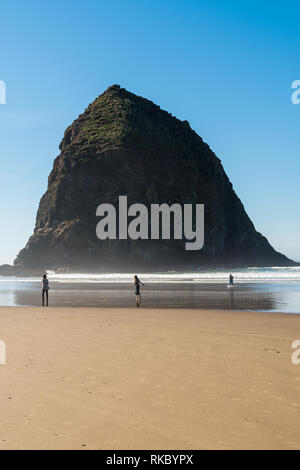 Touristen und Einheimische genießen den Strand mit Haystack Rock im Hintergrund bei Cannon Beach, Oregon, USA. Stockfoto