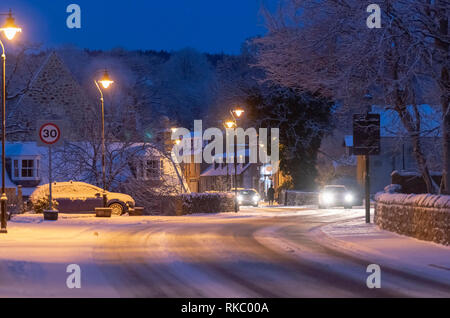 Verkehr macht seinen Weg durch Kincardine O'Neil vor Sonnenaufgang auf der A 93 noch mit Schnee bedeckt Stockfoto