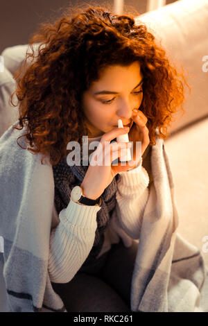 Curly Frau Hand beobachten mit nasenspray nach erkältungsgefahr Stockfoto