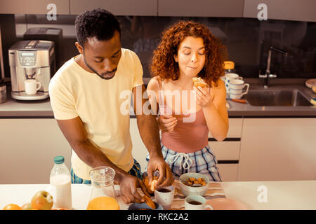 Curly rothaarige Frau kauen ihre leckeren morgen Croissant Stockfoto