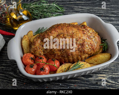 Gebratenes Schweinefleisch Roulade, Rolle mit Kartoffeln und Tomaten in Backblech Stockfoto