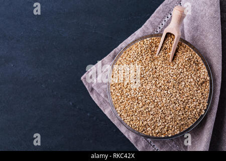 Weiße Sesamsamen in Glasschale auf darck Hintergrund Draufsicht, Platz für Text. Vegan protein Quelle. Superfoods und gesunde Lebensmittel sauber essen. Stockfoto