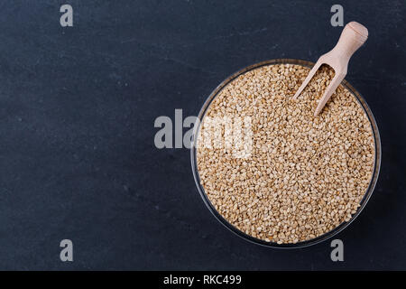 Weiße Sesamsamen in Glasschale auf darck Hintergrund Draufsicht, Platz für Text. Vegan protein Quelle. Superfoods und gesunde Lebensmittel sauber essen. Stockfoto