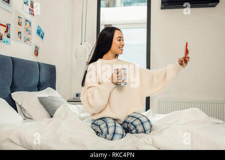 Dunkelhaarige Frau mit bequemen rosa Pullover, selfie Stockfoto