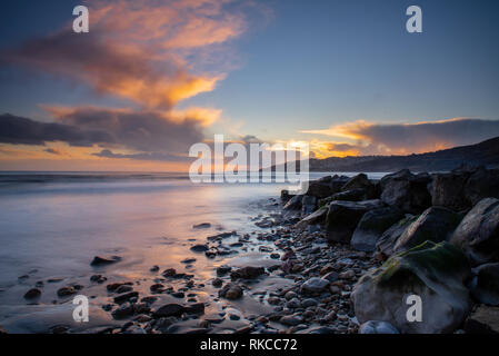 Charmouth, Dorset, Großbritannien. 10. Februar 2019. UK Wetter: Die moody Abend Himmel bei Charmouth blühen vibrant orange Farbe bei Sonnenuntergang am Sonntag abend eingestellt. Nach einem Wochenende der starken Winde und Regen durch Sturm Erik eine Zeit der Ruhe und Mehr nieder Wetter für den Südwesten diese Woche prognostiziert ist. Credit: PQ/Alamy leben Nachrichten Stockfoto