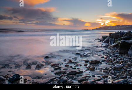 Charmouth, Dorset, Großbritannien. 10. Februar 2019. UK Wetter: Die moody Abend Himmel bei Charmouth blühen vibrant orange Farbe bei Sonnenuntergang am Sonntag abend eingestellt. Nach einem Wochenende der starken Winde und Regen durch Sturm Erik eine Zeit der Ruhe und Mehr nieder Wetter für den Südwesten diese Woche prognostiziert ist. Credit: PQ/Alamy leben Nachrichten Stockfoto