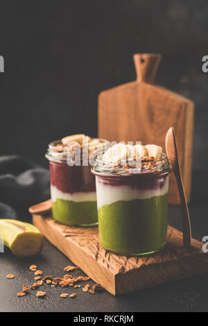 Rainbow Smoothie in Jar für Frühstück. Gesunde detox vegan Smoothie oder Parfait garniert mit Müsli und Banane Stockfoto