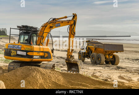 SWANSEA, WALES - Oktober 2018: Bagger und Lkw Umzug Stapel von Sand am Strand von Swansea nach dem Winde an der Küste geblasen hatte. Stockfoto