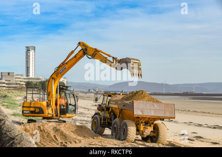 SWANSEA, WALES - Oktober 2018: Bagger Beladen eines Lkw mit Sand am Strand von Swansea nach dem Winde an der Küste geblasen hatte. Stockfoto